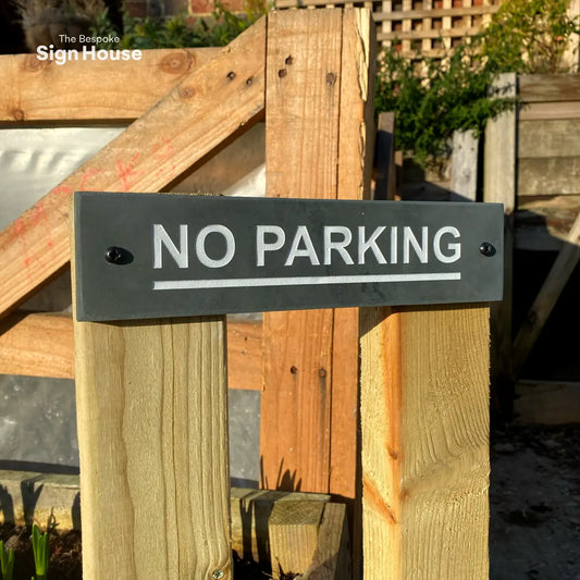 a slate sign on wooden posts outdoors that reads No Parking in white