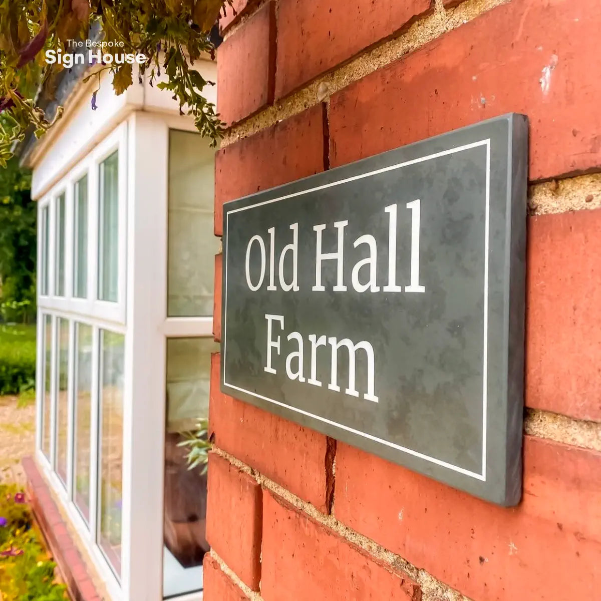 a large house sign on a red brick wall, with a straight border design