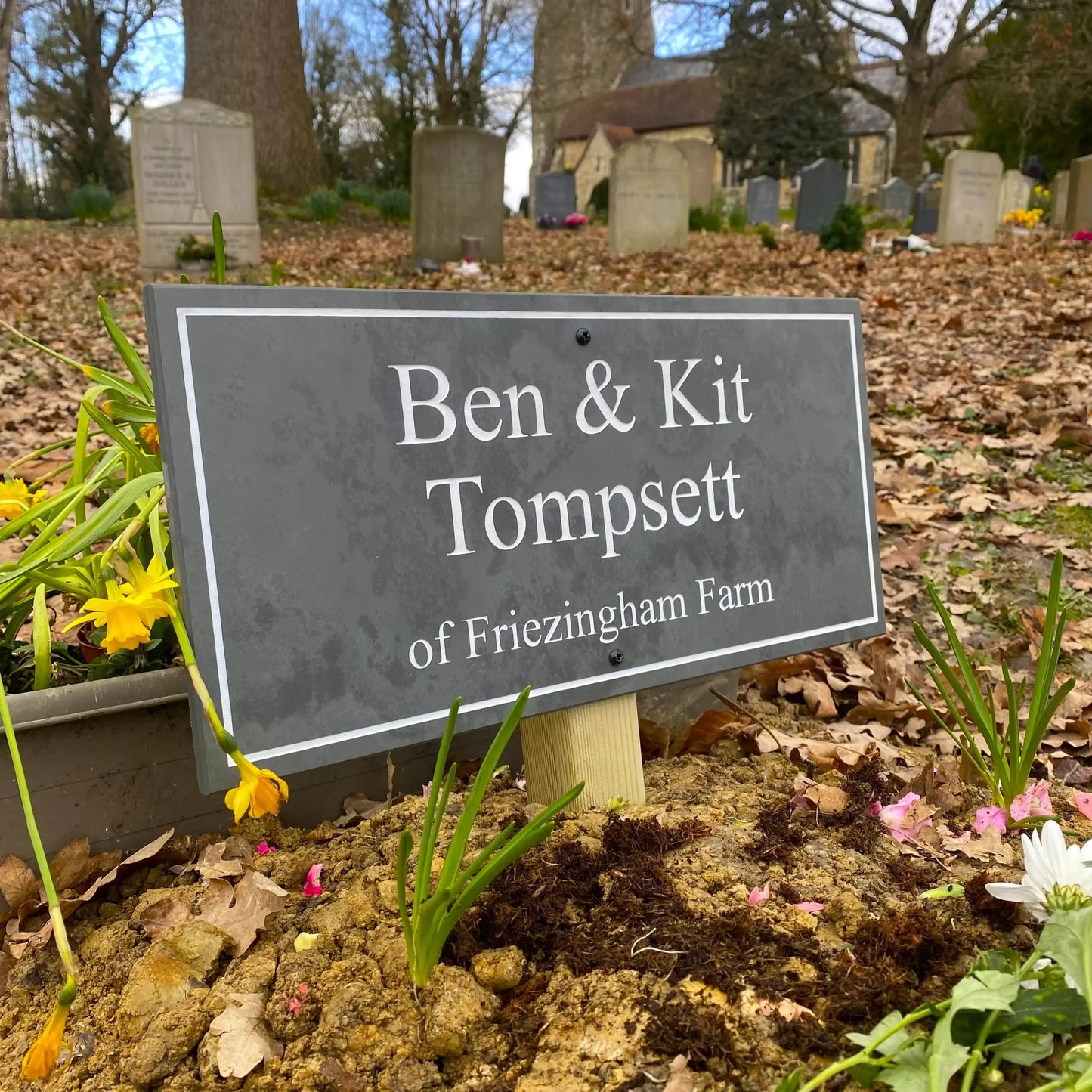 grey headstone with engraved name on wooden post