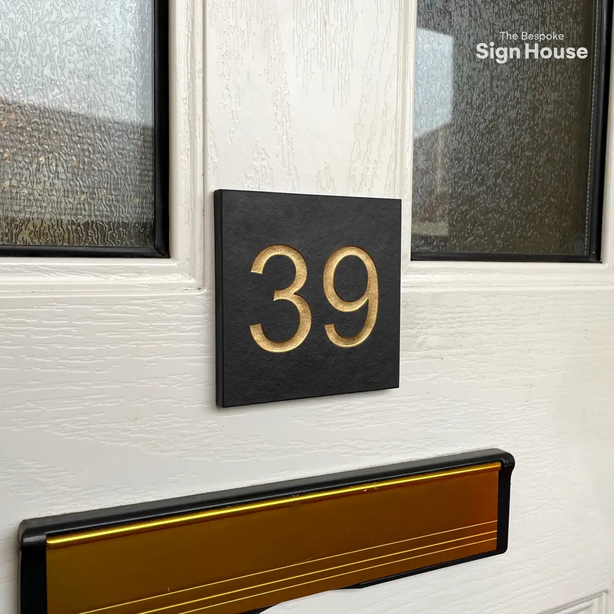 Square gold painted slate sign fixed to a uPVC front door