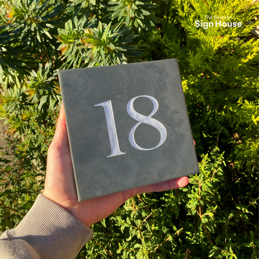 a house number sign with 18 engraved into a square slate tile