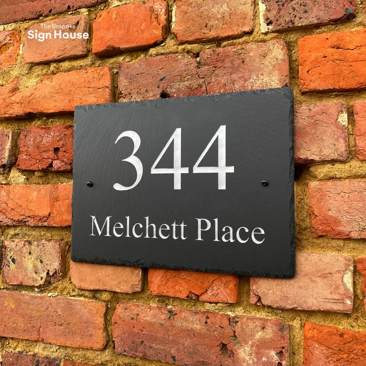 a chiselled welsh slate house sign with house number and name engraved in silver 