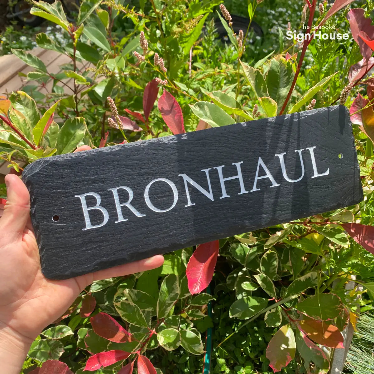 long shaped welsh slate sign with the house name Bronhaul engraved into the surface and then hand painted white