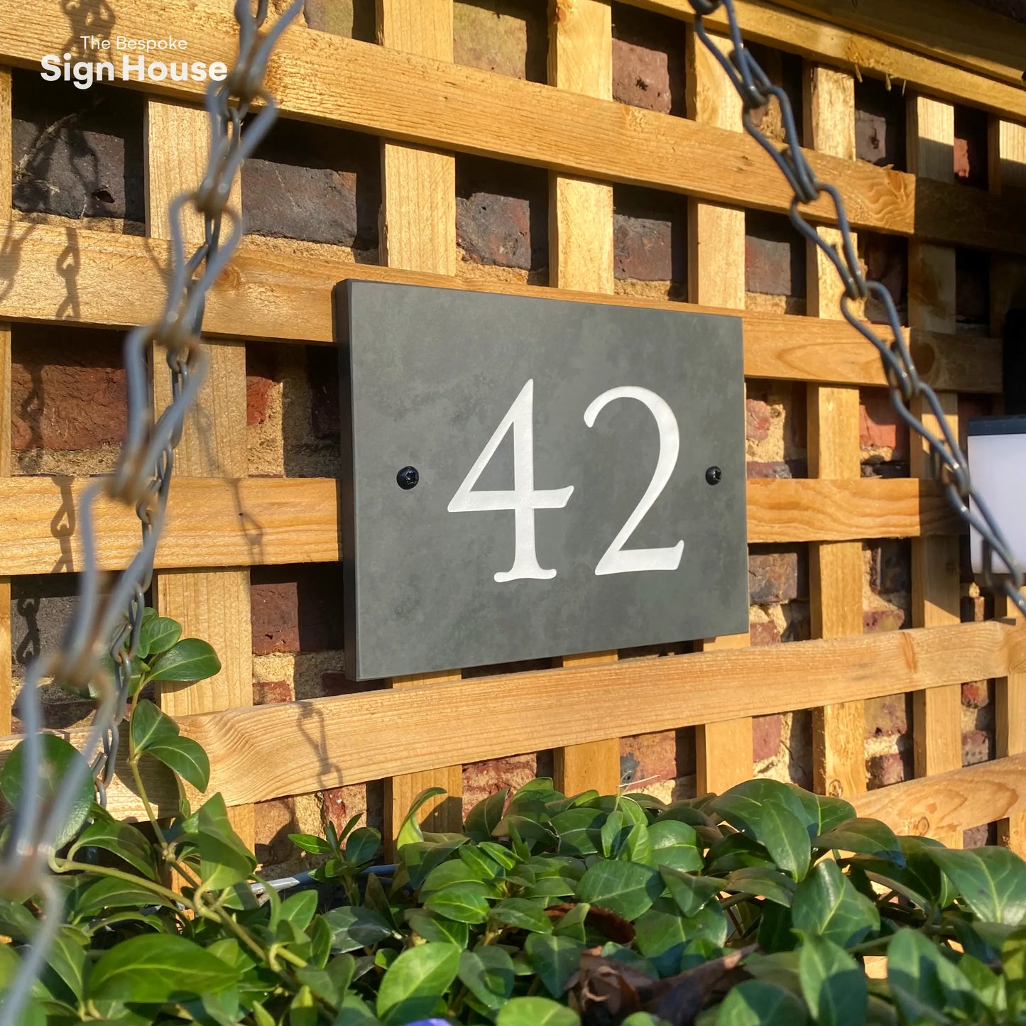 slate number plaque with engraved 42 in white paint on front of house.